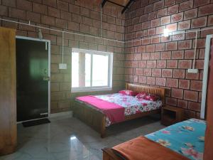 a bedroom with two beds in a brick wall at Nature Spot Cottages in Kurchi