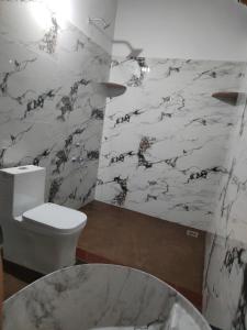 a bathroom with a toilet and a marble wall at Nature Spot Cottages in Kurchi