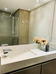 a bathroom with a sink with a mirror and flowers at Itaim Bibi - The Capital Flat - Apto 1211 in Sao Paulo