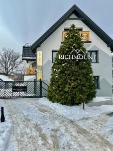 a christmas tree in front of a building in the snow at Richmount Apartamenty Karpacz in Karpacz