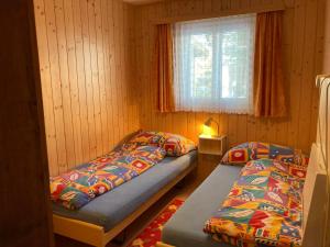 2 camas en una habitación pequeña con ventana en Chalet Sunnuterrasse en Rosswald
