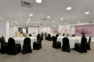 uma sala de conferências com mesas brancas e cadeiras pretas em Athenaeum Grand Hotel em Atenas
