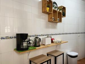 eine Küche mit einer Theke mit Kaffeemaschine und Hockern in der Unterkunft El rincón de Jesús y Loli in Córdoba