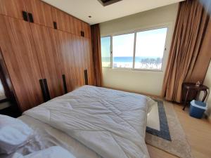 a bedroom with a large bed with a large window at الشقة البحرية الدهاريز in Salalah