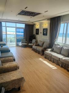 una gran sala de estar con sofás, sillas y ventanas. en الشقة البحرية الدهاريز, en Salalah