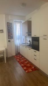 una cucina con armadi bianchi e un tappeto rosso sul pavimento di Casa Gemelli Roma a Roma