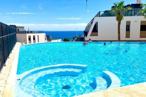 a large blue swimming pool with the ocean in the background at 5 Apartamento Iconic Beach in Gran Alacant