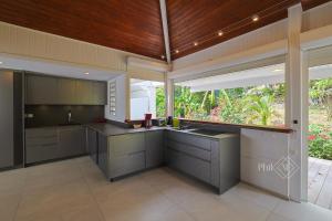 a kitchen with gray cabinets and a wooden ceiling at Magnifique villa rénovée neuve à Orient Bay in Saint Martin