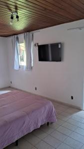 a bedroom with a bed and a flat screen tv at Chalé do riacho 1 in Itatiaia