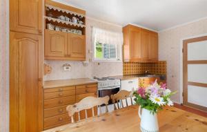 a kitchen with wooden cabinets and a table with a vase of flowers at 5 Bedroom Cozy Home In Strandebarm in Strandebarm