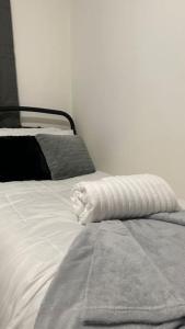 a white bed with a towel on top of it at Cozy 3 bedroom House in Great Billing
