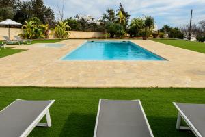 a swimming pool in a yard with two chairs at New! Villa Can Blai in Santa Eularia des Riu