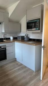 a kitchen with white cabinets and a microwave at Cozy 3 bedroom House in Great Billing