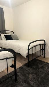 two beds in a room with white walls at Cozy 3 bedroom House in Great Billing