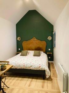 um quarto com uma cama com uma parede verde em Gite de la Chapelle option SPA em Verchocq