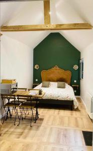 um quarto com uma parede verde com uma cama e uma mesa em Gite de la Chapelle option SPA em Verchocq