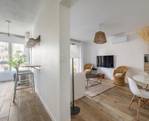 a living room with white walls and a table and chairs at Face à l'Arbre Blanc, Neuf Clim Parking in Montpellier
