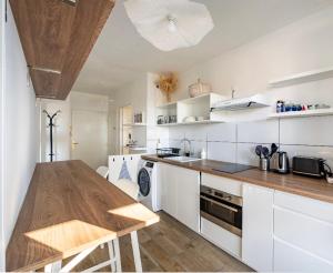 a kitchen with white cabinets and a wooden table at Face à l'Arbre Blanc, Neuf Clim Parking in Montpellier