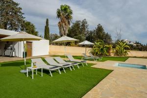 a lawn with chairs and umbrellas and a pool at New! Villa Can Pere Blai in Santa Eularia des Riu