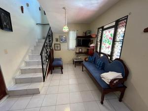 ein Wohnzimmer mit einem blauen Sofa und einer Treppe in der Unterkunft Sana El Jardin Secreto in Santiago de los Caballeros