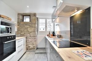 una cucina con armadi bianchi e un muro in pietra di Maison Castine - Maison pour 6 a Saint-Cast-le-Guildo Altre 9 foto