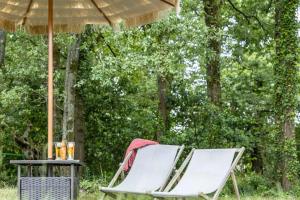 two chairs and a table under an umbrella at Propriété idéale pour coworking/voyage entreprise in Treillières