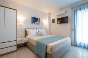 a white bedroom with a bed and a television at ALMIRA Studios Limnos 2 in Mirina