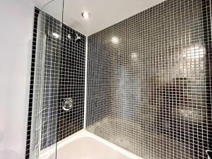 a bathroom with a shower with black tiled walls at Beachfront Bliss with Spectacular Views in Llanelli