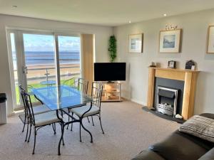 a living room with a table and chairs and a television at Beachfront Bliss with Spectacular Views in Llanelli
