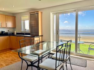 cocina con mesa de cristal y sillas con vistas a la playa en Beachfront Bliss with Spectacular Views, en Llanelli