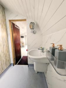 a white bathroom with a sink and a toilet at Glamping Pod for 2 Pod Beag Na Haun Eriskay in Eriskay