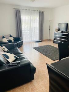 sala de estar con sofá negro y TV en Casa Blanca, en Alicante