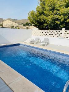 una piscina con tumbonas junto a una pared blanca en Casa Blanca, en Alicante