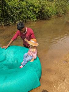a man and a young child sitting on an inflatable at Nature Spot Cottages in Kurchi