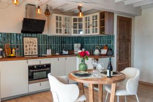 uma cozinha com uma mesa de madeira e armários brancos em Domaine de la Baie de Somme, suite Vanadis em Cayeux-sur-Mer