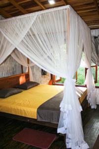 1 dormitorio con cama con dosel y cortinas blancas en Seasons Four Eco Friendly Treehouse en Matara