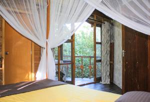 1 dormitorio con 1 cama y ventana con balcón en Seasons Four Eco Friendly Treehouse en Matara