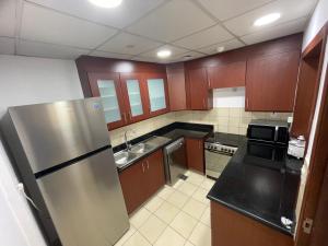 a kitchen with wooden cabinets and a stainless steel refrigerator at Sea View Beach Hostel - Walk to Beach - Metro Station - Pool in Dubai