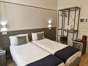 um quarto com uma cama grande com lençóis brancos e almofadas em Boutique Hôtel Neptune Nice em Nice