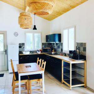a kitchen with black cabinets and a wooden table and chairs at Boinot Lodge in Le Château-dʼOléron