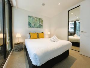 - une chambre avec un grand lit blanc et des oreillers jaunes dans l'établissement 2BR 1 Bath, Dockland, Marvel Stadium, Spacious, à Melbourne