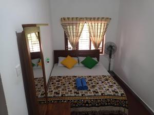 a bedroom with a bed with colorful pillows and a window at The Villa Hush in Hikkaduwa