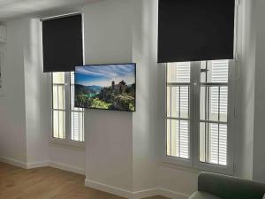 uma sala de estar com três janelas e uma televisão na parede em Résidence Terminus - appartements em Sainte-Maxime