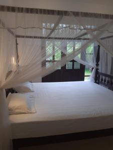 a bed with white sheets and a canopy at Villa La more in Unawatuna +25 photos