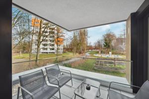 einen Balkon mit Stühlen und Blick auf einen Spielplatz in der Unterkunft Sali Homes/ R1 Gemütliches Apartment am Fluss in Bayreuth