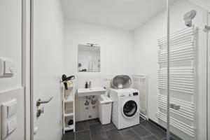 ein weißes Badezimmer mit einer Waschmaschine und einem Waschbecken in der Unterkunft Sali Homes/ R1 Gemütliches Apartment am Fluss in Bayreuth