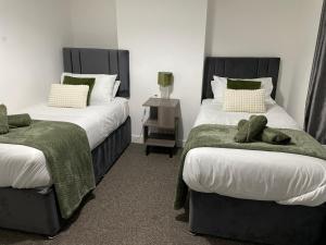 1 dormitorio con 2 camas y toallas verdes. en House for Contractors and Families, en Aldershot
