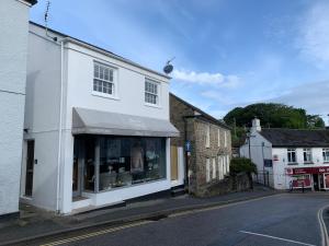 a white building with a store window on a street at Lovely flat, balcony & woodstove, parking close in St. Agnes