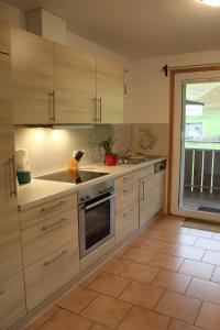 eine Küche mit Holzschränken und einem großen Fenster in der Unterkunft Sport Rees - Ferienwohnung Melanie in Oberried