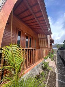 uma casa de madeira com um alpendre e algumas plantas em Volcano Cabins em Kubupenlokan